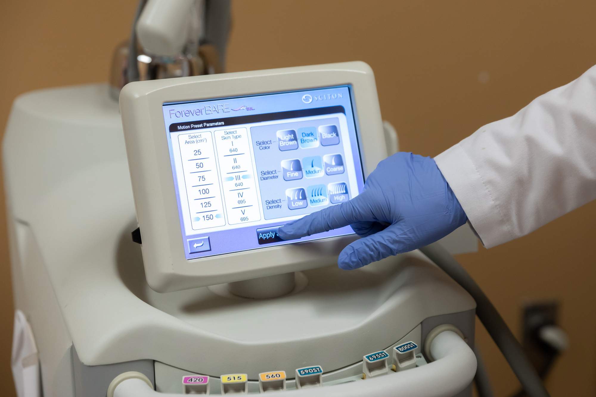 A specialist with blue gloves uses a machine for laser hair removal near Mattoon